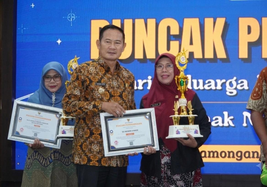 Bupati Lamongan Yuhronur Efendi menyerahkan penghargaan kepada Salamah, S.Pd, M.Pd Kasek SDN IV Made peraih juara I Sekolah Ramah Anak, pada acara Harganas ke-33 dan HAN) ke-42 di Pendopo Lokatantra Lamongan, Kamis (6/8/2026). (FT/dok)